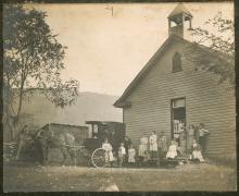 Book wagon with horse outside of school house with school children