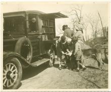 Book wagon on country road; women, children and a dog