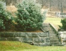Image of stone wall and stair case with bushes on each side
