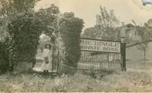 Woman standing under trestle; gate says "The Dingle, Private Road"