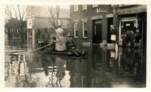 Photograph of flooded street in Hancock Maryland; 5 men in boat rowing through street