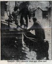 Newspaper clipping of woman being rescued from flooded home; 2 men, 1 in boat and 1 on porch