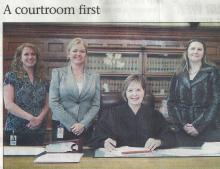 3 women standing, 1 woman seated in courtroom in front of bookcase; left to right are, Michelle Strietbeck, Dawne D. Lindsay, Judge Diane O. Leasure, and Amy McDonald