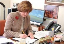 Photo of Carol Gaffney at office desk writing note with pencil