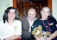 Photo of trio, 1 women holding teddy bear; Germaine Broussard, Robert Fratkin and Vickie Doolan-Fearon