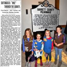 News article title "Suffragists "Hike" Through the County"; Photo of marker for Garrett County Pilgrimage with 4 Girl Scouts standing in front 