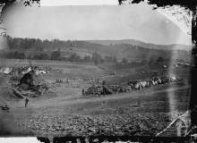 Photo of huts covered in straw and white tents along open field; used as hospital after Battle of Antietam, 1862