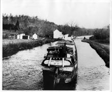 Canal in river approaching a lock, buildings on left side