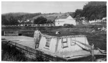 Woman standing on deck of canal boat with a hat on