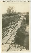 Conococheague aqueduct, a stone bridge; wood planks on top with several men working on repairs