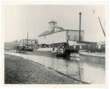 Darby Grain Mill near canal, boat in canal and freight train on track near mill