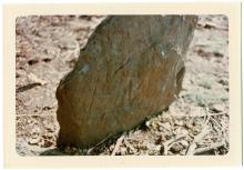 Large rock, this gravestone has "M.W." scraped into it