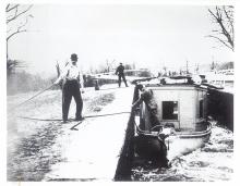 A paymaster's boat rises in a lock, 2 men with ropes tying the boat up 