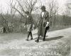 Young boy and Librarian walking on road carrying a basket of books