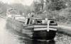 Canal boat in river with man steering boat at top 