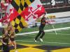 Photo of man running on football field holding flag of Maryland
