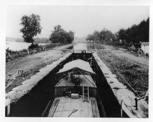 Two boys sit on boat in a lock, waiting to head downstream circa 1920s