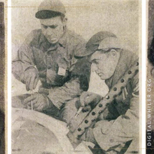 Two soldiers working on a bomber from World War II