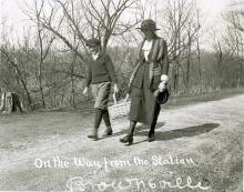 Young boy and Librarian walking on road carrying a basket of books