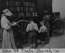 Book wagon parked with 1 man and 4 young children standing, reading books