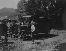 Bookwagon on country road; 3 men standing outside of wagon