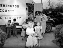 Children carrying books from bookmobile