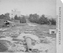 Antietam National Cemetery in 1877, canons scattered throughout; large white building in background