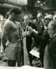 Boxer stands on scale to weigh in for competition; judges stand around in background