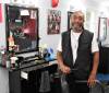 Barber Derik Stephens poses in front of his barbershop chair seat